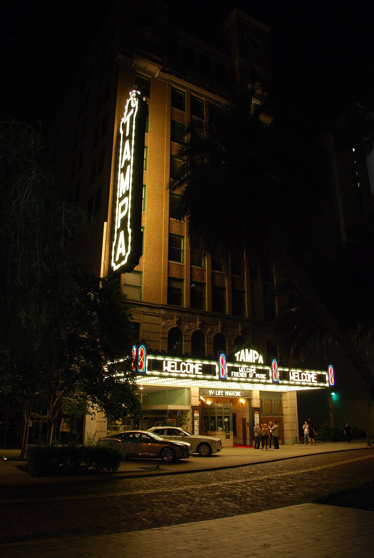 The lit marquee and neon blade sign of the historic Tampa Theatre at night